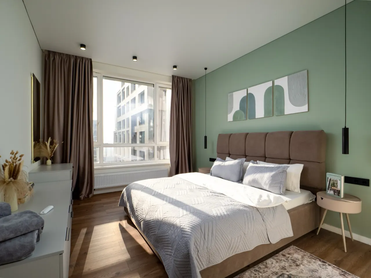 Bedroom with sage-green accent wall and king-size bed