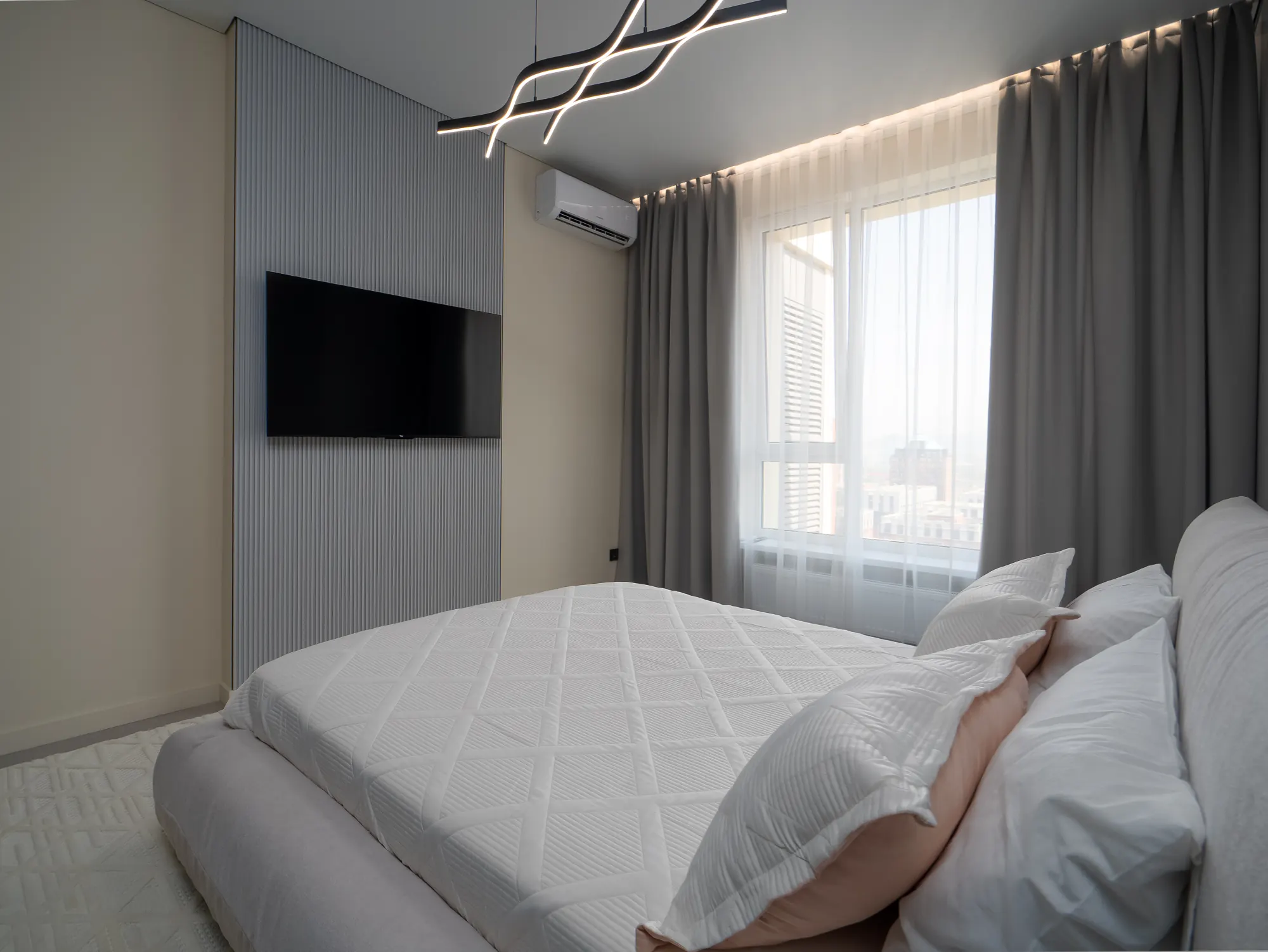 Bed dressed in white linen beside the window